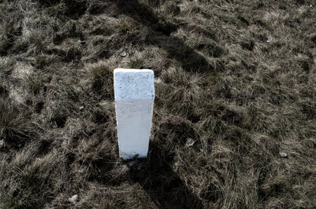 White concrete pillar in the grass on a hillside in winter.の写真素材