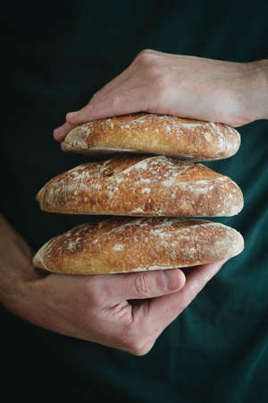 Baked bread of sourdough in hands. Artisan bread. The bread of sourdough, homemade and natural creation. The sourdough has natural yeast, which makes the food healthier, as well as rich.の写真素材