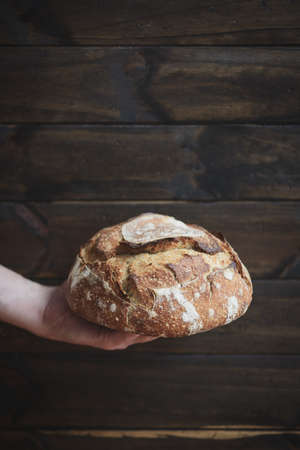 Baked bread of sourdough in hands. Artisan bread. The bread of sourdough, homemade and natural creation. The sourdough has natural yeast, which makes the food healthier, as well as rich.の写真素材