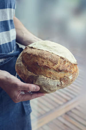 Baked bread of sourdough in hands - The bread of sourdough, homemade and natural creation. The sourdough has natural yeast, which makes the food healthier, as well as rich.の写真素材