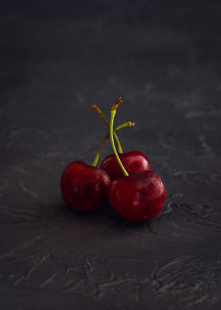 Three cherries on dark background. Close-up.の写真素材