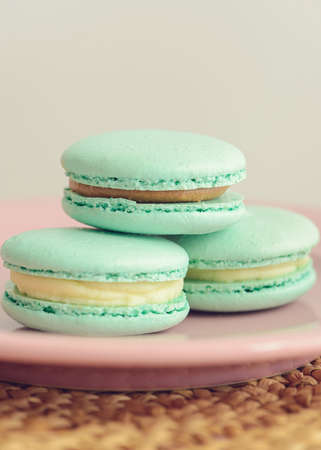 Three green macaroons on pink plate. Close up photo. Vertical photos. Delicious macaroons.の写真素材