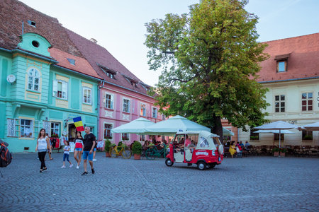Sighisoara, Romania - August, 2019: The main square with typical traditional architectural style in medieval citadel of Sighisoara, restaurants and souvenir shops. City in the middle of Transylvaniaのeditorial素材