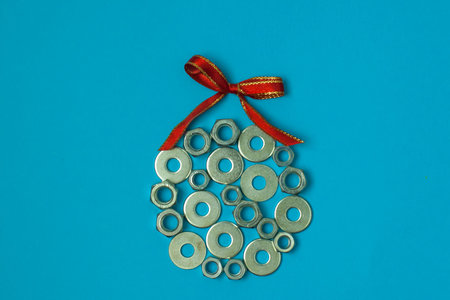 Christmas ball from washers and nuts on blue paper. Metal nuts. washers and grovers. Industrial new year concept background. Christmas card holiday greetings.の写真素材