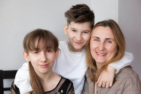 Happy mother and two children at home. portret of smiling mom hugging daughter and son. Concept of happy familyの写真素材