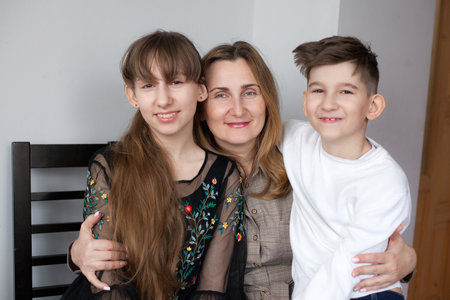Happy mother and two children at home. portret of smiling mom hugging daughter and sonの写真素材