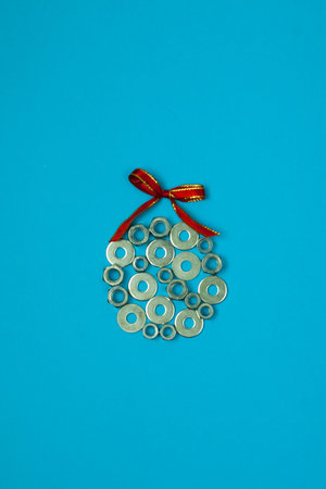 Christmas ball from washers and nuts on blue paper. Metal nuts. washers and grovers. Industrial new year concept background. Christmas card holiday greetings.の写真素材
