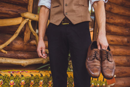 a groom and wedding shoes. Groom is wearing shoes outdoors. Male portrait of handsome guy. Beautiful model boy in colorful wedding clothes. Man is posing.の写真素材