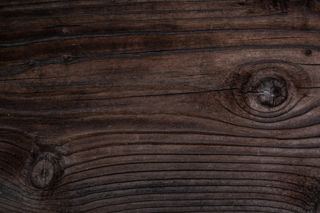 weathered dark brown wood background with texture. Texture of brown old wood. Wide burned board...
