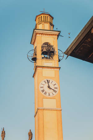 The bell tower with a clock of the old medieval cathedral on it in the sunset time. Beautiful...