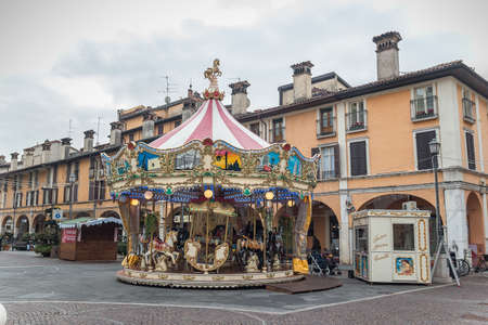 Brescia, Italy - December, 2015: Carousel Mary go round on Piazza del Mercato Market square in Brescia. Colorful Carousel Attraction Ride With Wooden Horses in a nothern Italian city at daytime.のeditorial素材