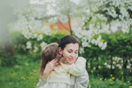 Happy mothers day. Little girl hugs her mother in the spring cherry garden. Portrait of happy mother...