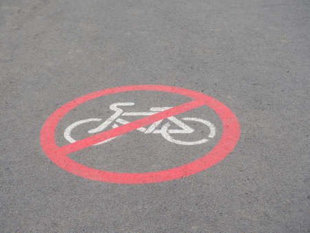 Road section with road markings regulating the movement of cyclists. No Biking Allowed. Circular white and red traffic sign. White bicycle Symbol Painted over gray Asphalt. Signs drawn on the pavementの写真素材