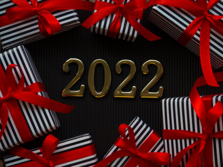 2022 on the black background. 2022 gold figures lie between small gifts in a stripped black and...