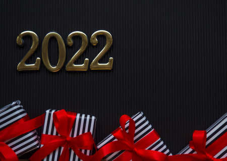 2022 on the black background. 2022 gold figures lie between small gifts in a stripped black and...