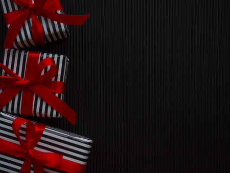 Gifts on the black background. Small gifts in a stripped black and white wrapper and with red...