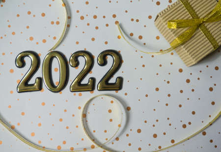 2022 on the white background. 2022 gold figures lie next to a small gift in a craft brown wrapper...