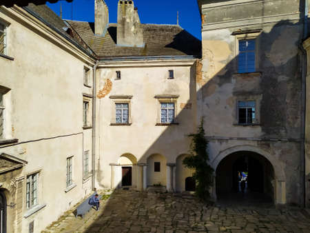 Olesko, Ukraine - October, 2019: Olesko Castle Courtyard in sunny autumn day. Tourists walking in Olesko Castle yard admiring ancient architecture view. Travelling in Lviv region of Western Ukraine.のeditorial素材