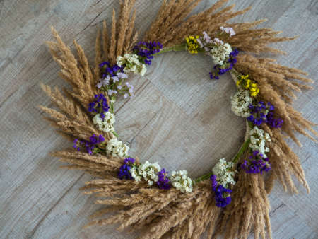 Creative autumn wreath with dried pampas grass and wildflowers on wooden background. space for text. hello fall. happy thanksgiving. Making a beautiful fall wreath for the decor from dried plants.の写真素材