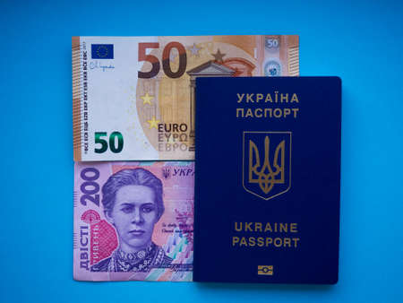 A set of European Union and Ukraine money with a face value of 50 euros and 200 hryvnia on blue. Background of the fifty euros, two hundred hryvnia banknotes and Ukraine passport with copy space.の写真素材
