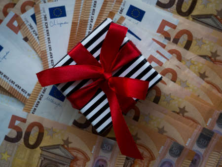 Wrapped gift box on the background of fifty euros banknotes. Set of European Union money with a face value of 50 euros. Enterprise capital investment, finance, savings, Christmas and New Year conceptの写真素材