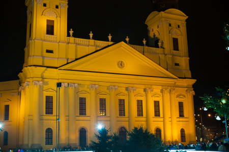 Debrecen, Hungary - December, 2021:Protestant Great Church, Hungarian: Reformatus Nagytemplom, on the Kossuth square. Close up of yellow buildings with two towers at Christmas time at nightのeditorial素材