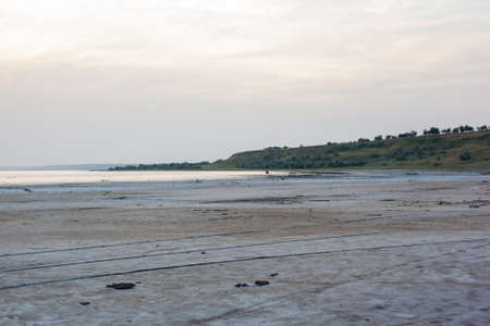 Dried up sandy estuary under the boundless sky. Twilight on the salt lake beach.
