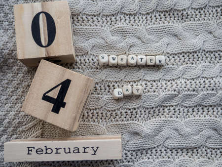 World sweater day. Beige background with text Sweater Day, date 4 February on wooden cubes and with place for your text. Copy space.の写真素材