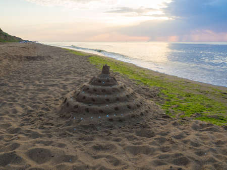 Built House sand castle with tower on the shore of the beach. Family travel concept with kids and tourism. Sand fortress built by children. Calmness relaxing on the beach in the morning.の写真素材
