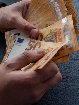 Background of the euros banknotes. Hands holding set of European money with a face value of 50 euros. The concept of business, Finance, and remuneration. Counting money for a rent, saving money.の写真素材