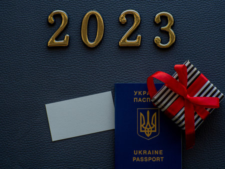 2023 gold figures lie near small gift in a stripped black and white wrapper and with red ribbons and...