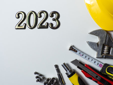 2023 with construction tools, yellow hard hat on white background with copy space. New Year and Christmas construction greeting card. For advertising or web design. Repair home at Christmas. Flat lay.の写真素材