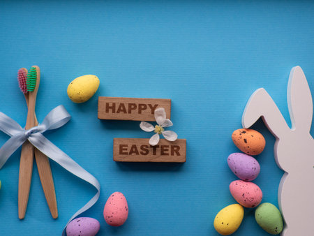Happy Easter and dentist concept. Wooden toothbrushes with Easter decorations on blue background. Dentist Easter greating card. Top view, flat lay. Bamboo toothbrushes, colorful eggs, white bunny.の写真素材