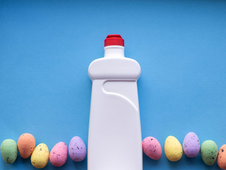 Happy Easter and cleaning concept. Detergent with Easter decorations on blue background with copy space. Easter greating card. Top view, flat lay. Cleaning stuff, colorful egg. Housekeeping. Mockup.の写真素材