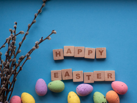 Happy Easter concept. Easter decorations on blue background with copy space. Easter greating card. Flat lay. Colorful eggs and Happy Easter inscription on wooden cubes. Celebration of spring holidays.の写真素材