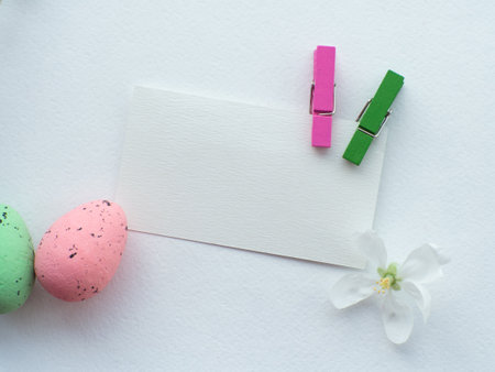 Happy Easter, white concept. Easter decorations on white background with copy space. Easter greating card. Flat lay. Apple flower, green and pink eggs. Celebrating Easter holidays.の写真素材