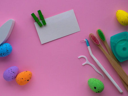 Happy Easter and dentist concept. Wooden toothbrushes with Easter decorations on pink background. Dentist Easter greating card with copy space. flat lay. Toothbrushes, eggs, bunny and dental floss.の写真素材