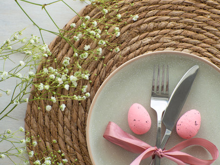 Festive Easter table setting with eggs and flowers on straw background, flat lay. Elegance pastel...