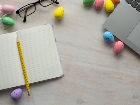 Easter work concept. Flat lay. Business work desk with devices and happy easter holiday multicolored eggs on wood background. Spring decoration workplace with gadgets. Work day on Easter holidays.の写真素材