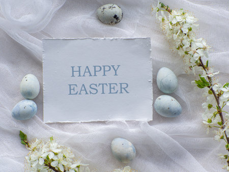 Blue painted easter eggs. Dyed Easter eggs with marble stone effect light blue color on white tablecloth background with cherry blossom. Eggs background with Happy Easter. Holiday postcard concept.の写真素材
