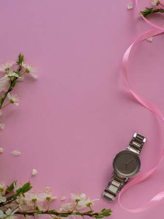 Womens hand watch on pink background with cherry flowers and copy space. Womens, Valentines and Mothers Day gift. Concept of beauty, elegance and femininity. Buying birthday gifts online.の写真素材