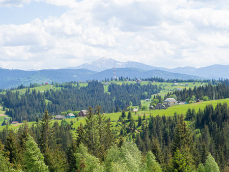 Carpathian landscape with cloudy sky. Green meadows in mountains near forest. Lifestyle in the Carpathian region. Ecology protection concept. Explore the beauty of the world.の写真素材