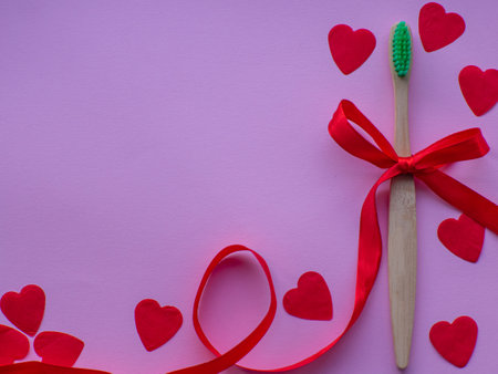 Flat lay with a lot of tiny heart-shaped papers, toothbrush and space for text. Red heart paper background with toothbrush tied with a red bow. Valentines day dentist concept. February 14th.の写真素材