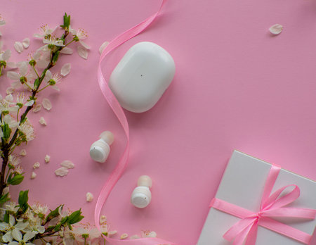 White wireless headphones on pink background with cherry flowers, gift box and copy space. Womens, Valentines and Mothers Day gift. Concept of music and elegance. Buying birthday gifts.の写真素材