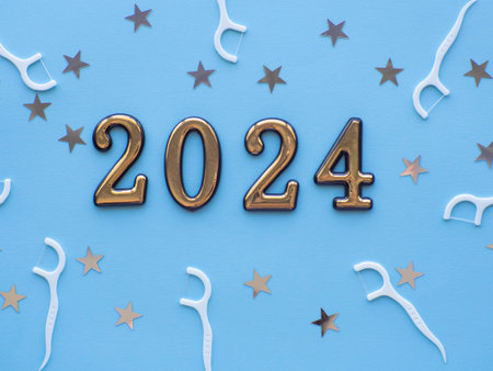 2024 and dental concept. Close up view photo with 2024 and white dental floss sticks on blue background with copy space for text. Christmas medical card. Merry Christmas and Happy New Yearの写真素材