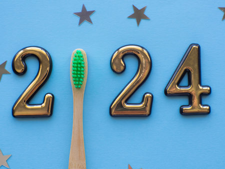 2024 and dental concept. Close up view photo with 2024 and wooden green toothbrush instead zero on blue background with copy space for text. Christmas medical card. Merry Christmas and Happy New Yearの写真素材
