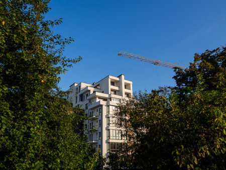 Luxury residential flat. Facade of a modern apartment building on a sunny day. House with a blue sky and construction crane. Modern elements in contemporary architecture.の写真素材