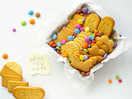 Assorted cookies and candies in the basket with Love you mom note. mothers day concept. Handmade care package, seasonal gift box with candies, dragee and cookies for mother on Valentines or Womens Dayの写真素材