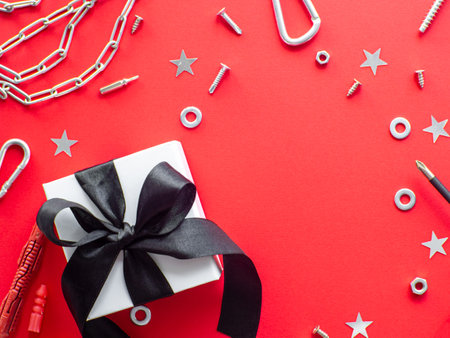 Construction tools and wrapped gift on red background with copy space. Construction greeting card for Christmas, Fathers, Mens or Valentines day. Repair home. Gifts for lover. Buying presents for man.の写真素材