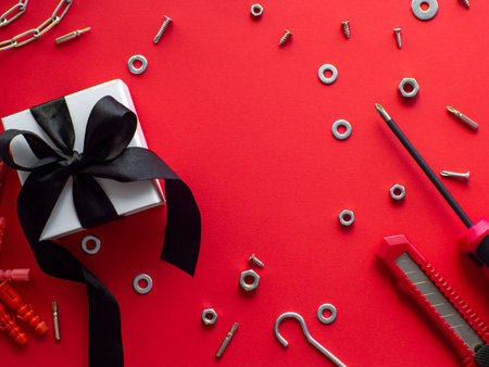 Construction tools and wrapped gift on red background with copy space. Construction greeting card for Christmas, Fathers, Mens or Valentines day. Repair home. Gifts for lover. Buying presents for man.の写真素材